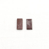 Dark red jasper cabochons are flat rectangles measuring approximately 16.3x8mm and 2.3.mm thick with beveled sides. Each opaque, polished stone is unique with inclusions forming patches and/or veins of beige, gray, and black.  Lighter-colored areas have more translucency than the rest of the stone.