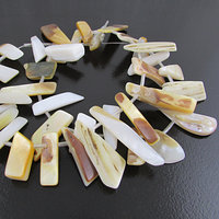 Graduated mother of pearl strand has 36 flat spike beads. Top-drilled irregularly shaped beads range from 10mm to 20mm long and 3mm. Beads are hand cut irregular shapes. One side is iridescent off-white nacre. The reverse side is polished, but retains the natural striated light brown color of the outer shell.