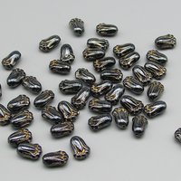 Opaque dark gray tulip-shaped pressed glass beads measure 12mm long, 8mm wide, 5.5mm thick. Center drilled lengthwise holes have an approximate diameter of 0.8mm. Beads are a shiny dark gray with a gold wash that highlights the details.