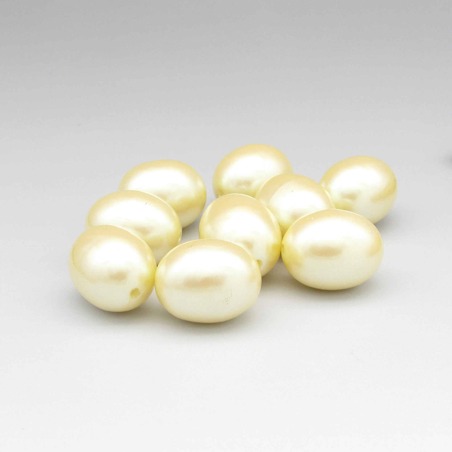 Vintage cream-colored plastic pearls are large oval beads measuring approximately 21.5mm long and 17mm wide. Lengthwise holes have a diameter of approximately 2mm,