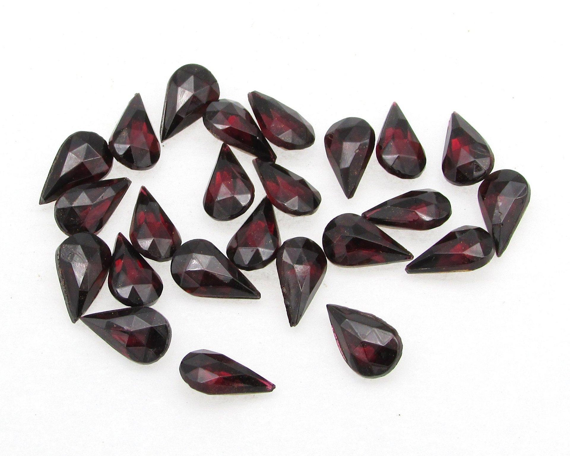 Vintage tin table cut pear shape rhinestones are translucent garnet red backed with gold foil. Point back stones measure 10mm long and 6mm wide.