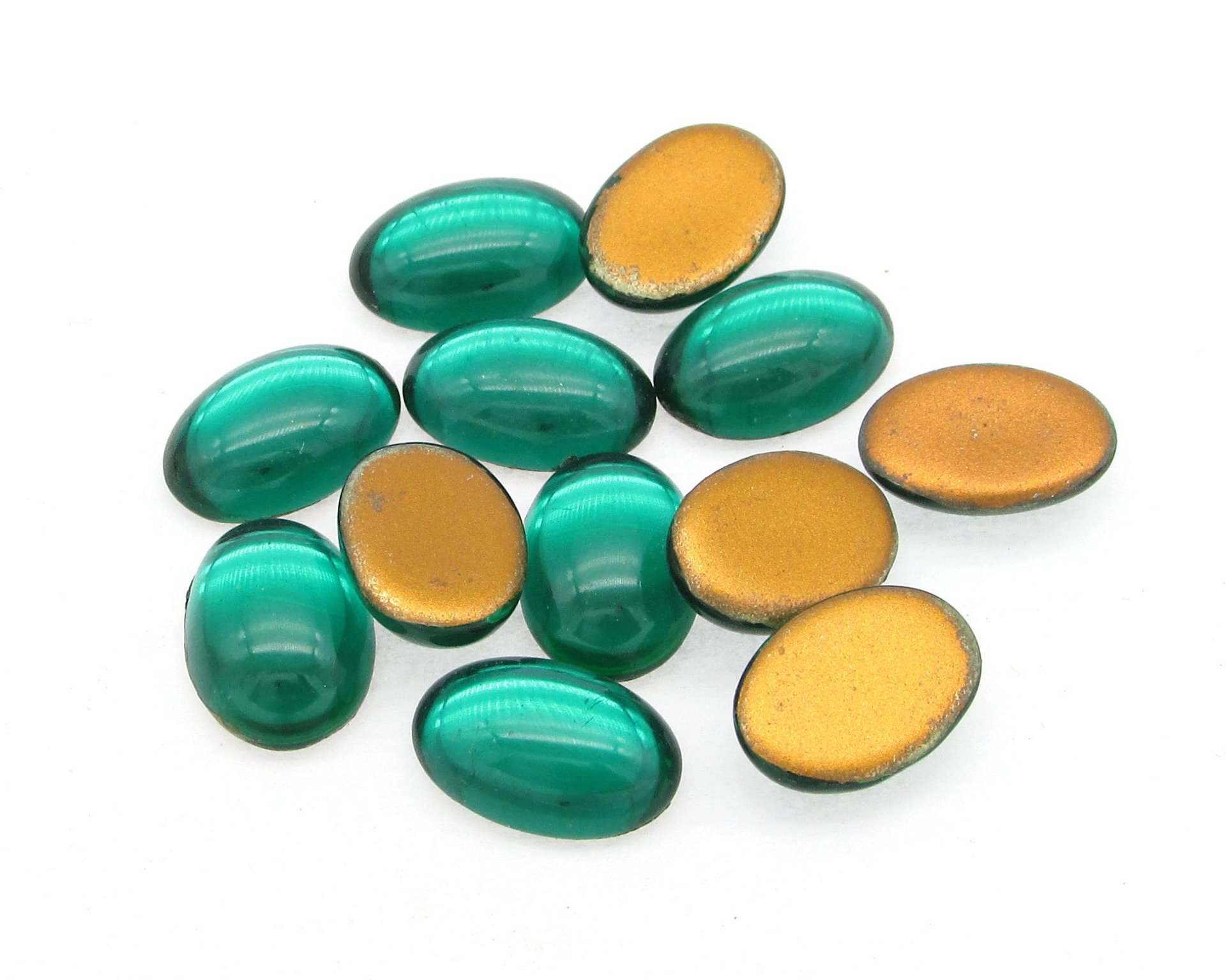 Vintage glass cabochons are translucent emerald green with gold foil. Flat back gems are 14mm long and 10mm wide, with a smooth 5mm dome. 