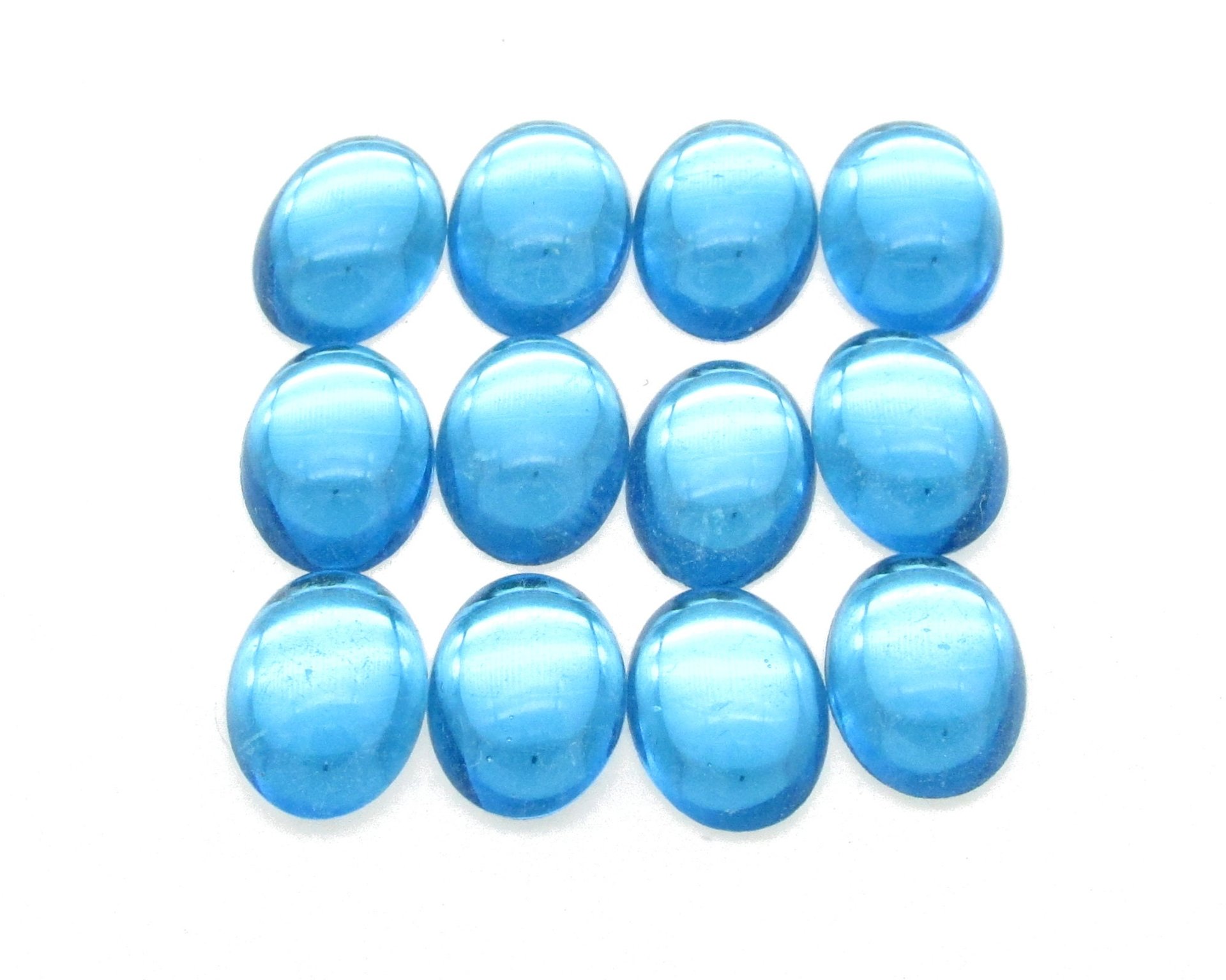 14x10mm vintage glass cabochons are translucent aquamarine blue. Smooth flat back gems have a 5mm dome and silver foiled backs.