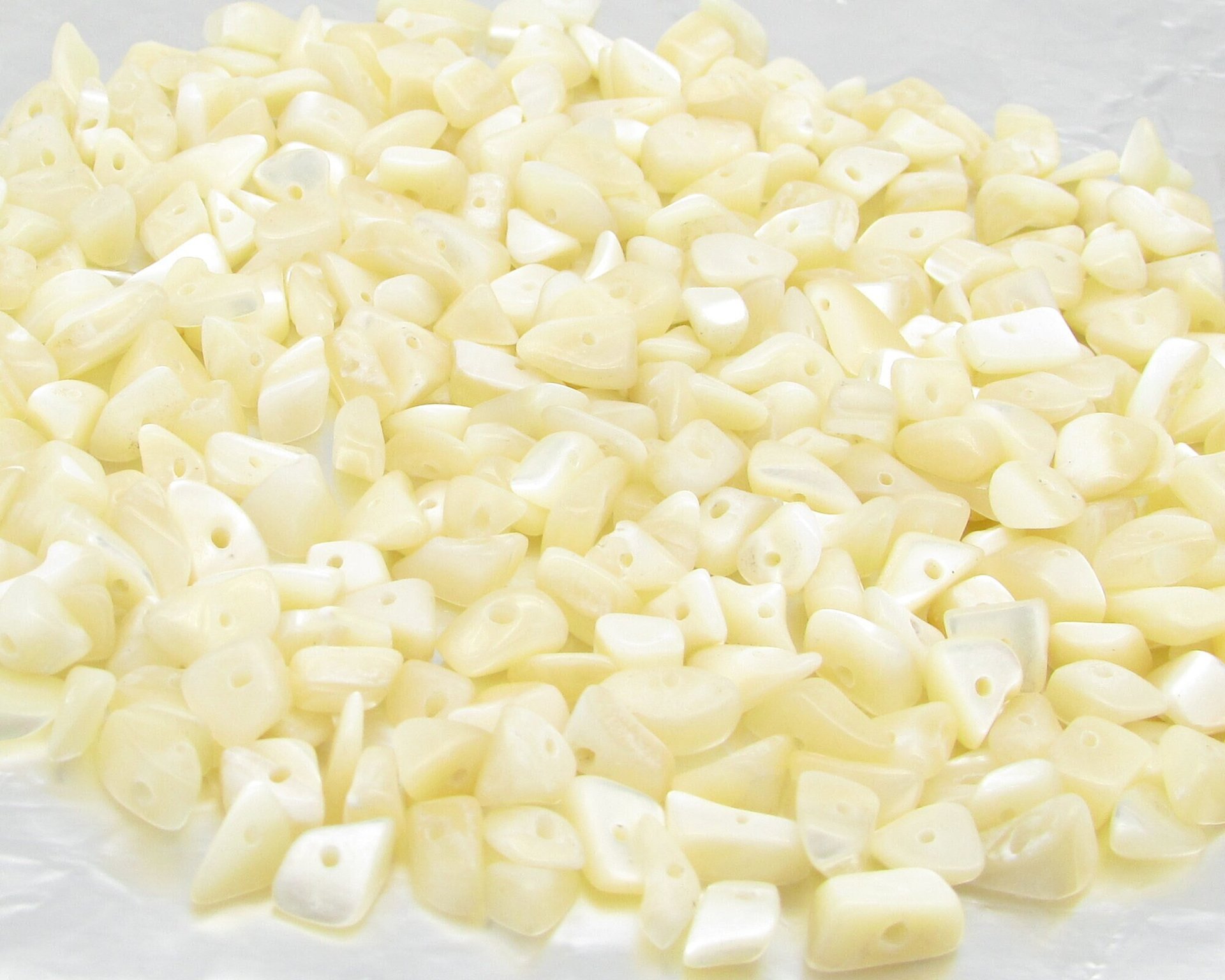 Lustrous, undyed mother of pearl chips are small freeform nuggets measuring approximately 5mm to 8mm long and 3mm to 5mm thick. Bead holes measure 0.8mm to 1.0mm in diameter.