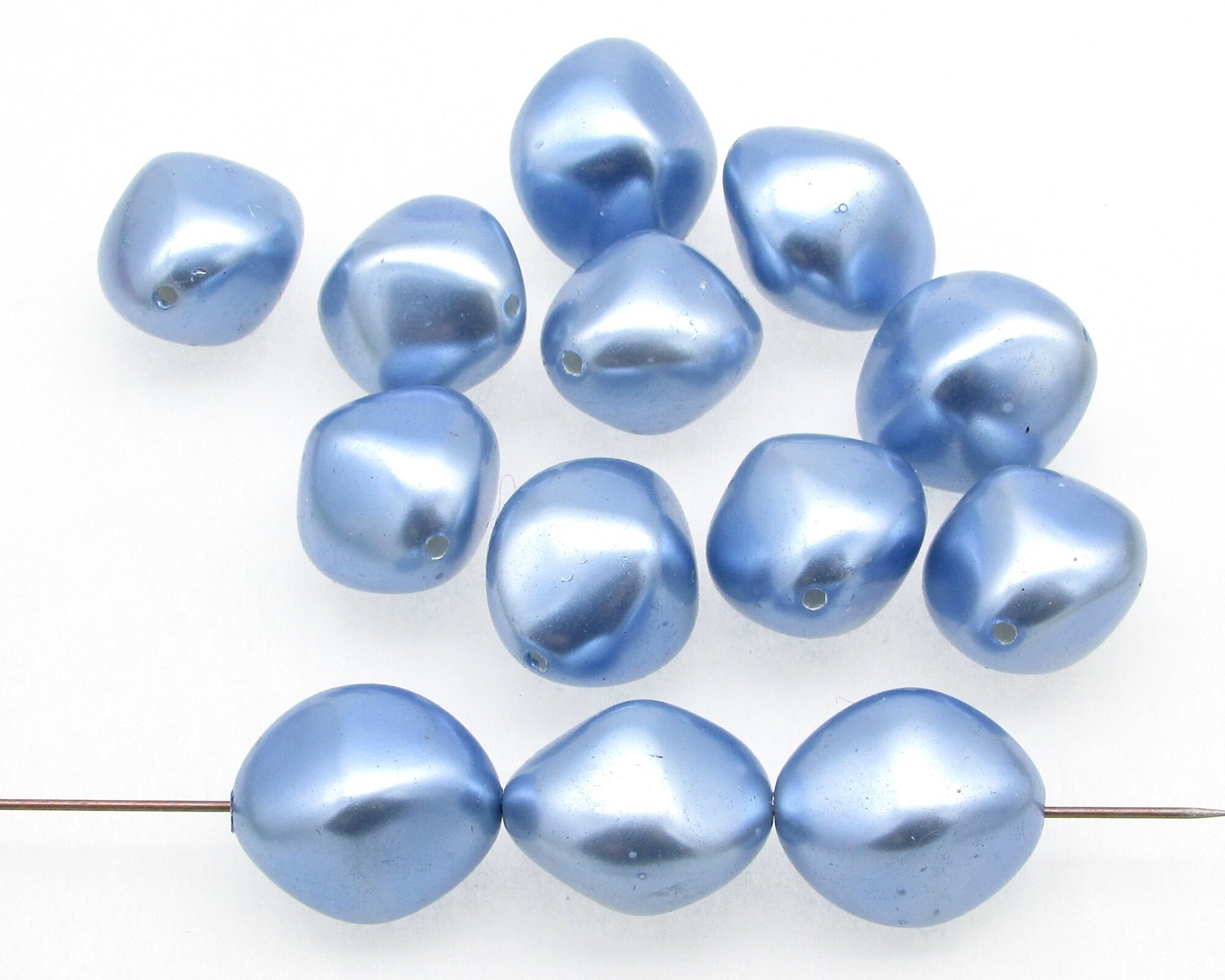 Lustrous, opaque blue plastic pearl bicone beads measure approximately 18mm long and 16mm wide. Center-drilled lengthwise holes are approximately 1mm. 