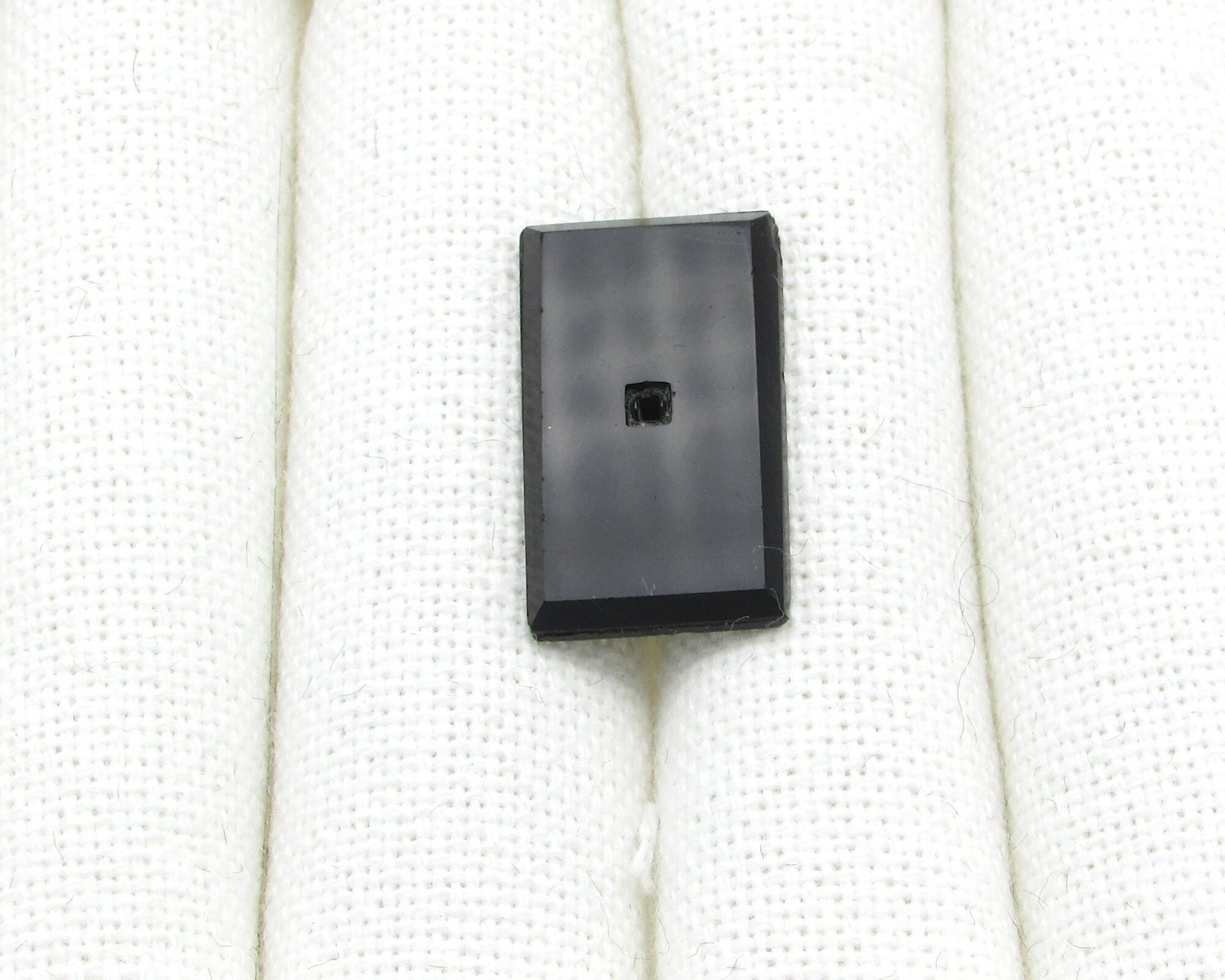 Rectangular glass stone has a flat table and a faceted back. Opaque black gem has an empty square beveled setting in the center to hold a tiny square rhinestone (sold separately).