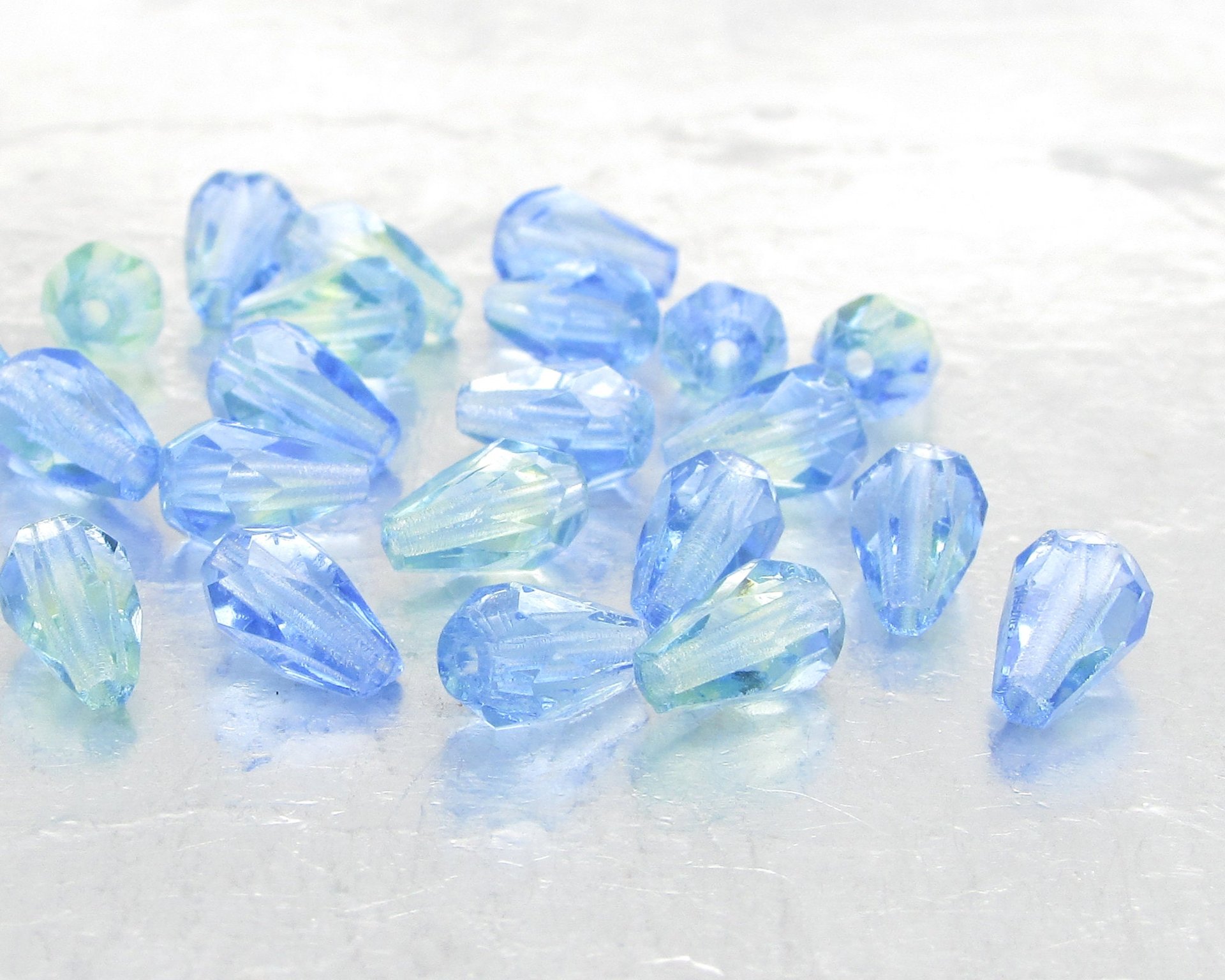 Small faceted teardrop beads are translucent two-tone peridot and sapphire blue Czech glass.