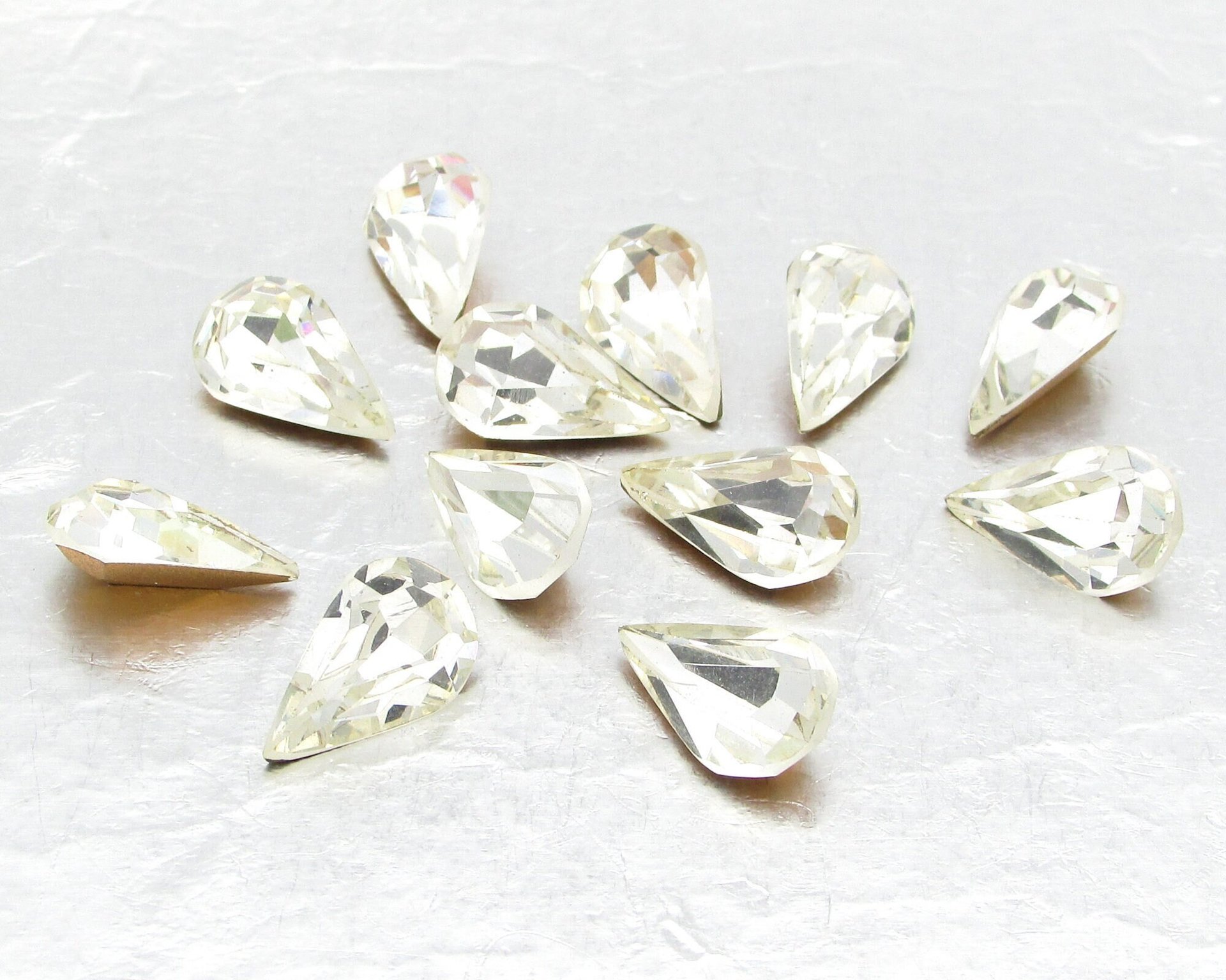 Vintage tin table cut pear shape rhinestones are clear crystal backed with gold foil. Point back stones measure 13mm long and 7.8mm wide.