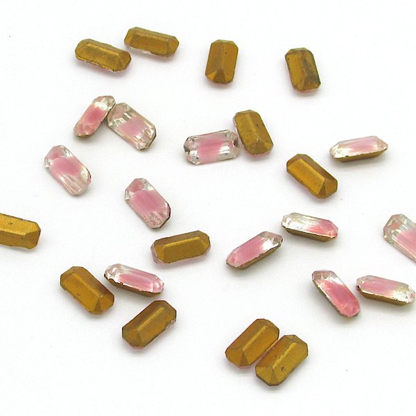 Vintage baguette rhinestones have opaque rose pink givre encased in clear glass. Narrow octagonal table cut stones measure approximately 10mm long, 5mm wide, and 3.5mm thick at center point. The pointed backs have gold foiling. These old, but unused, glass stones were made in Western Germany for couture beadwork.