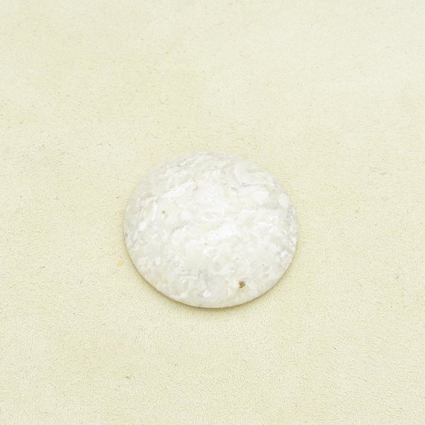 Opaque beige jasper cabochon is polished on both sides, with a domed top. Stone has mottled look, with lighter patches of cream and some small translucent areas. Low dome cabochon measures approximately 30mm across and 6mm thick at the center. 